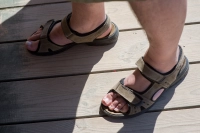 Person ifoert sandaler paa trae terrasse